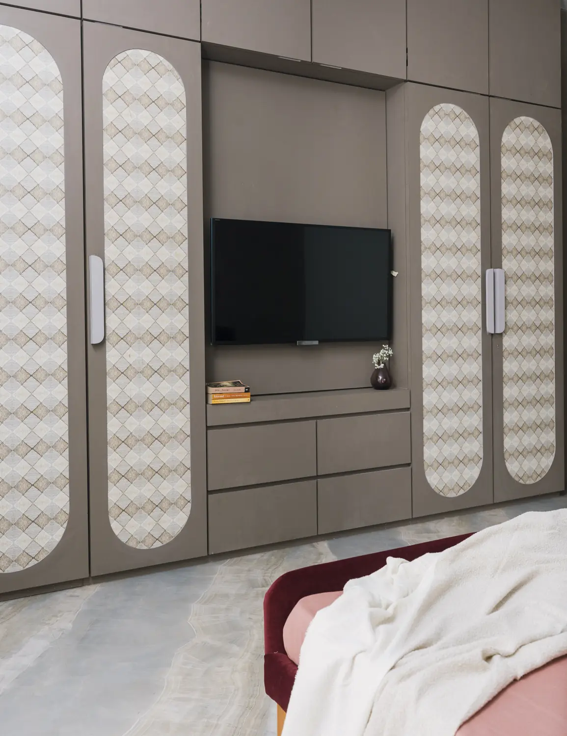 Wardrobe with arched patterned panels around a TV