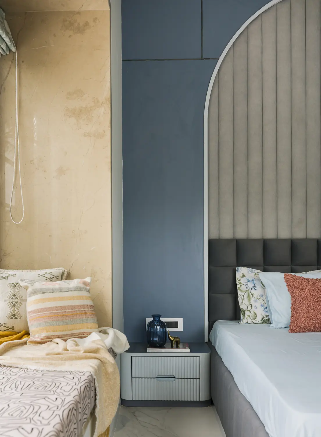 Blue arch beside a grey upholstered bed