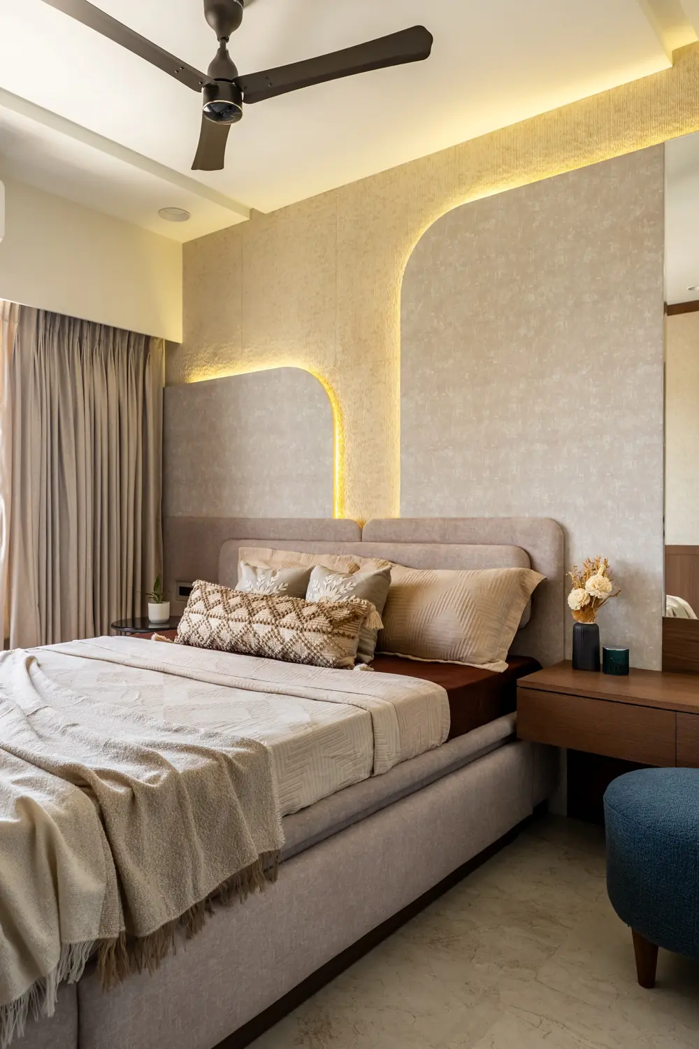 Bedroom with a curved, lit plaster wall behind the bed