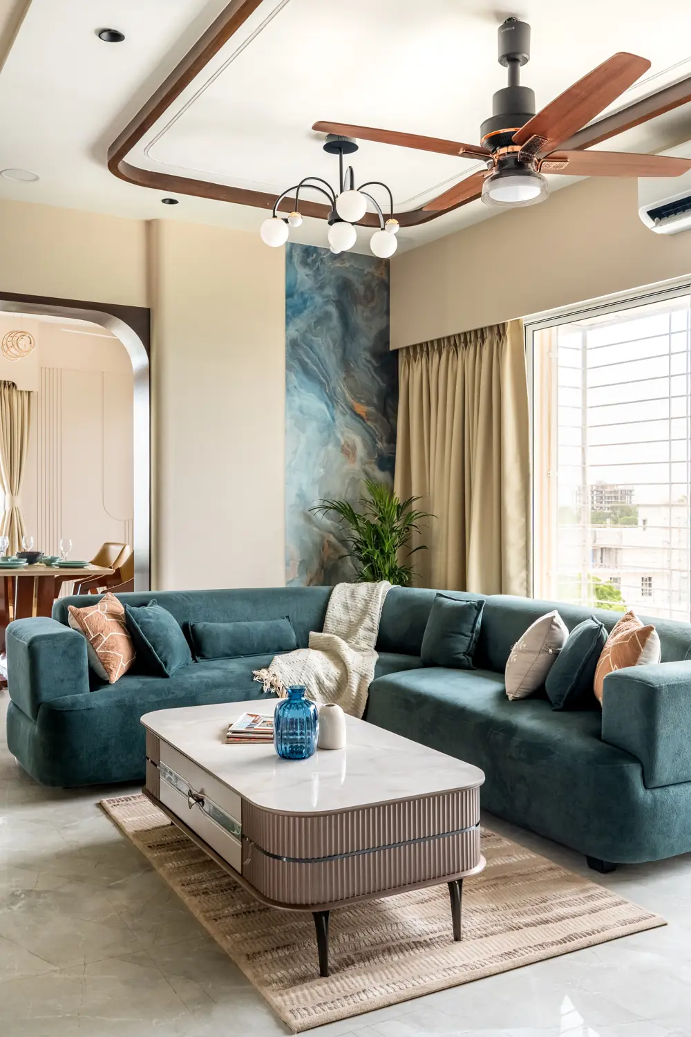 Living room with a teal sofa, carved ceiling and brass fan